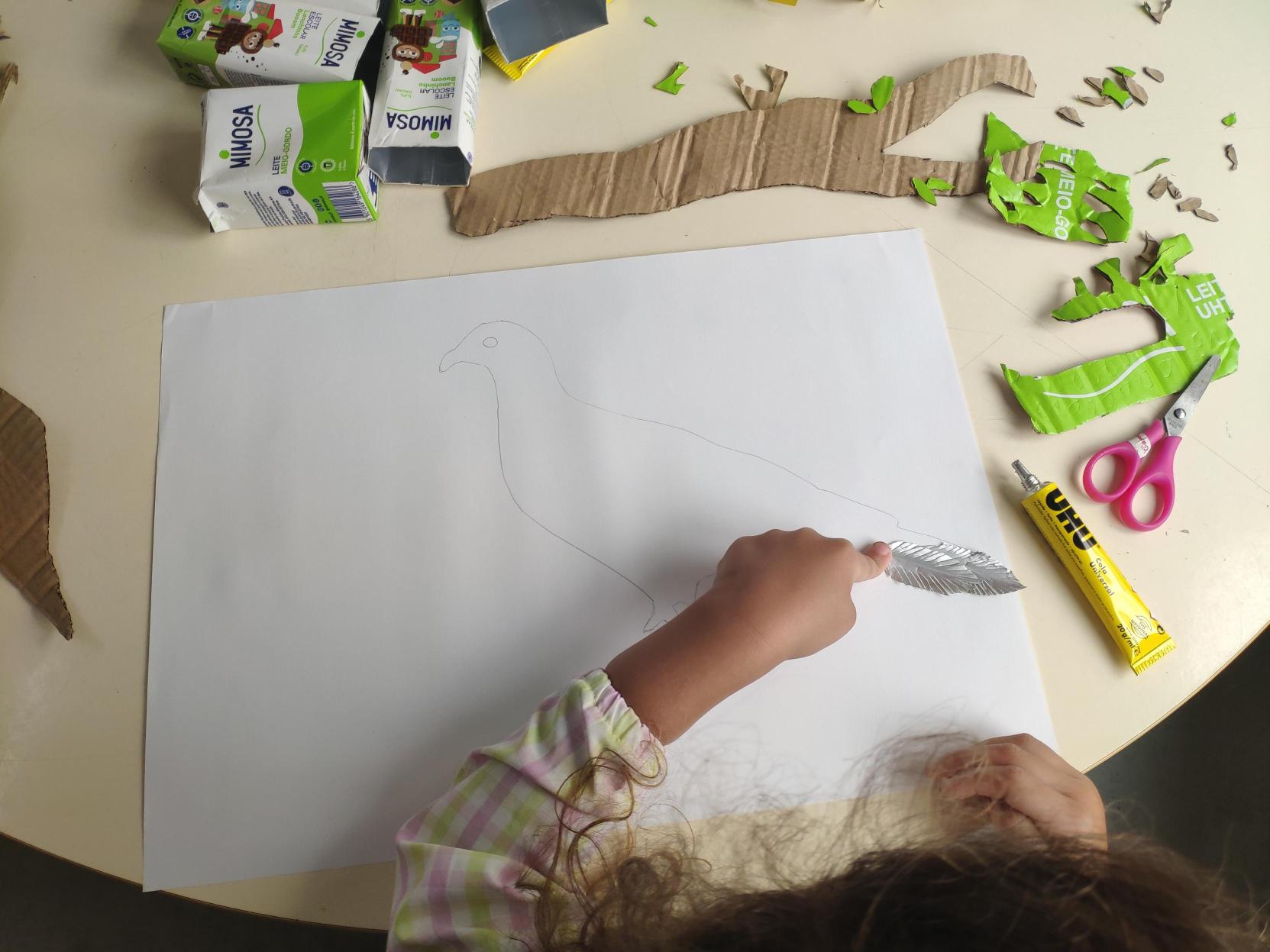 Montagem e colagem das penas elaboradas com cartão de embalagens de leite escolar.